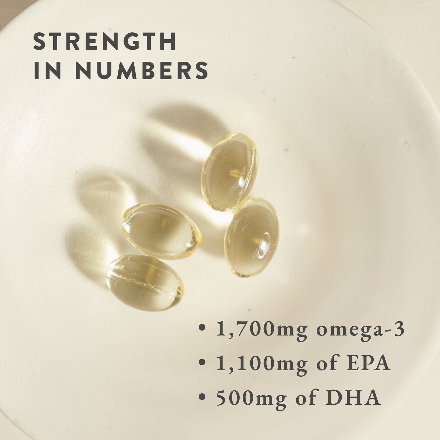 Four translucent Life & Soul Omega-3 Fish Oil Mini Capsules by Bare Biology sit on a white plate, captioned: Strength in numbers—1,700mg omega-3 per serving, with 1,100mg EPA and 500mg DHA.