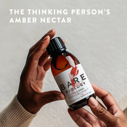 A person holds a bottle of Bare Biology Pure Omega-3 Liquid Fish Oil, with the words The thinking persons amber nectar above on a light background.
